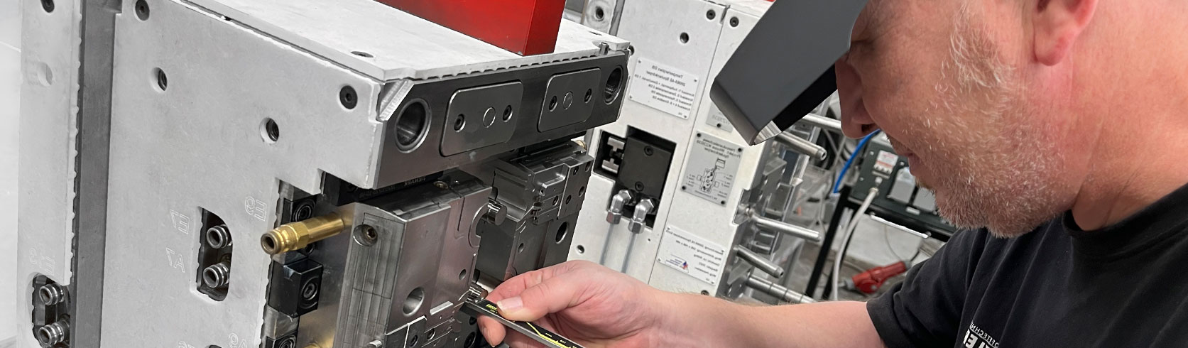 ein Mitarbeiteter der Firma Schnitzer Kunststoffe arbeitet mir der Lupenbrille sehr präzise an einem Spritzguss Werkstück